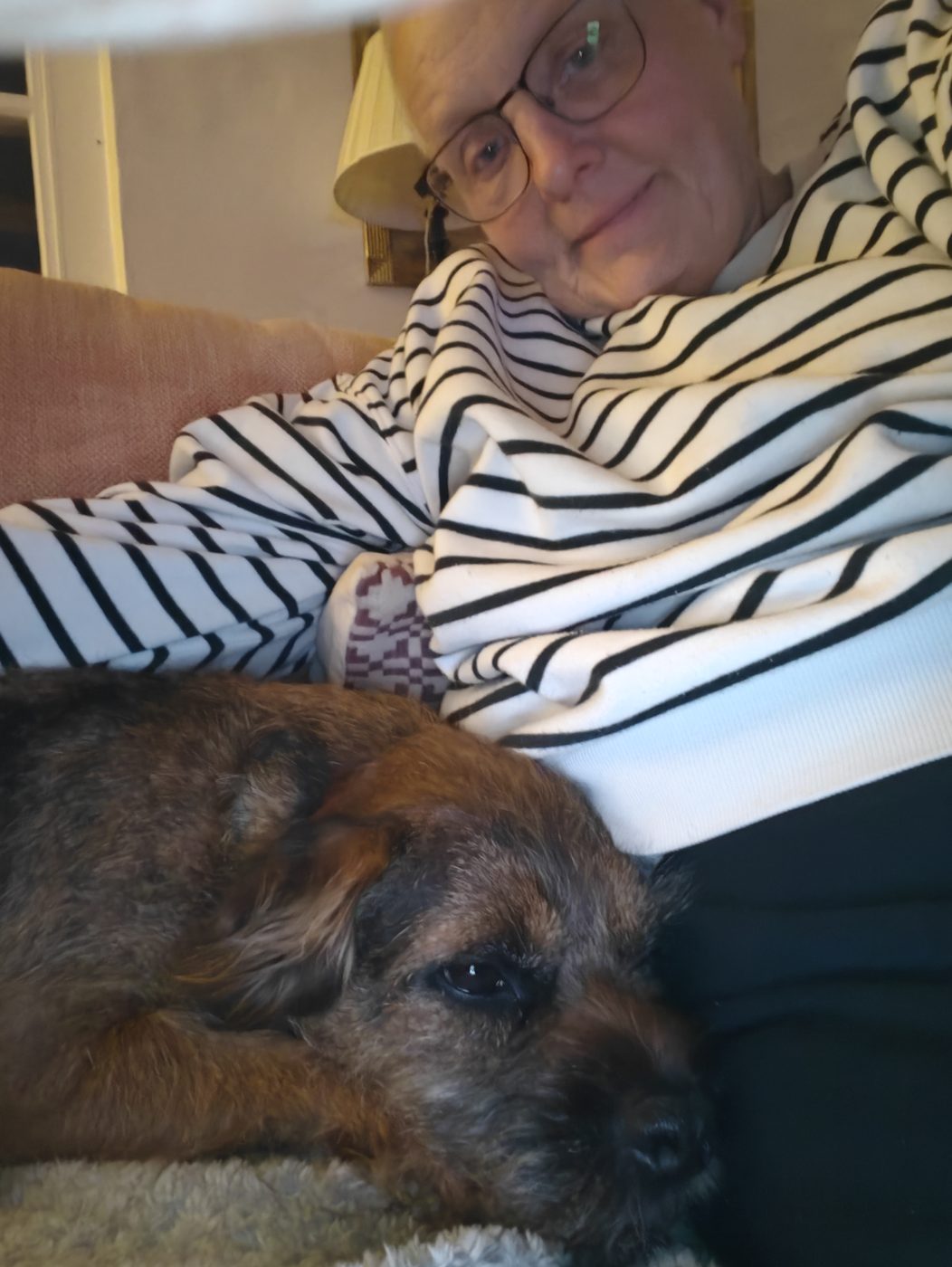 Michelle on the sofa with Finn, a border terrier, on her lap